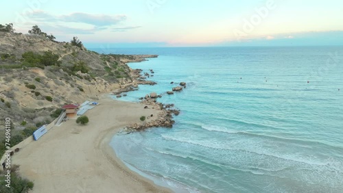 Aerial serene beauty of Konnos Beach in Ajia Napa, Cyprus. The cove is flanked by rugged hillsides and scattered rock formations, leading into the clear, turquoise waters of the Mediterranean. photo