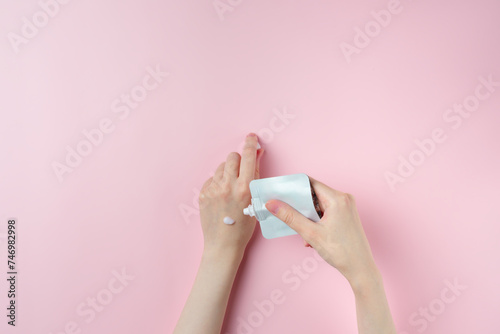 Female hand testing cream on pastel pink background © Solesto
