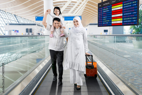Muslim family walking with a suitcase on the airport moving walkways photo