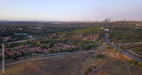 Renfe Cercanias commutes towards Madrid financial district at dusk. Train journey from Madrid's heart to tranquil suburban areas