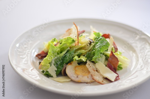 mixed leaf salad with bacon and chicken, parmesan dressing, white background, close-up view