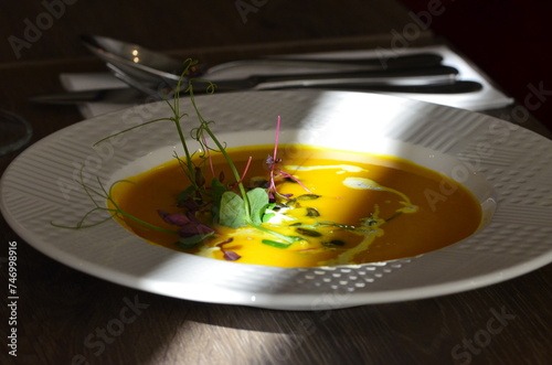 pumpkin soup, served in a restaurant, decorated with herbs