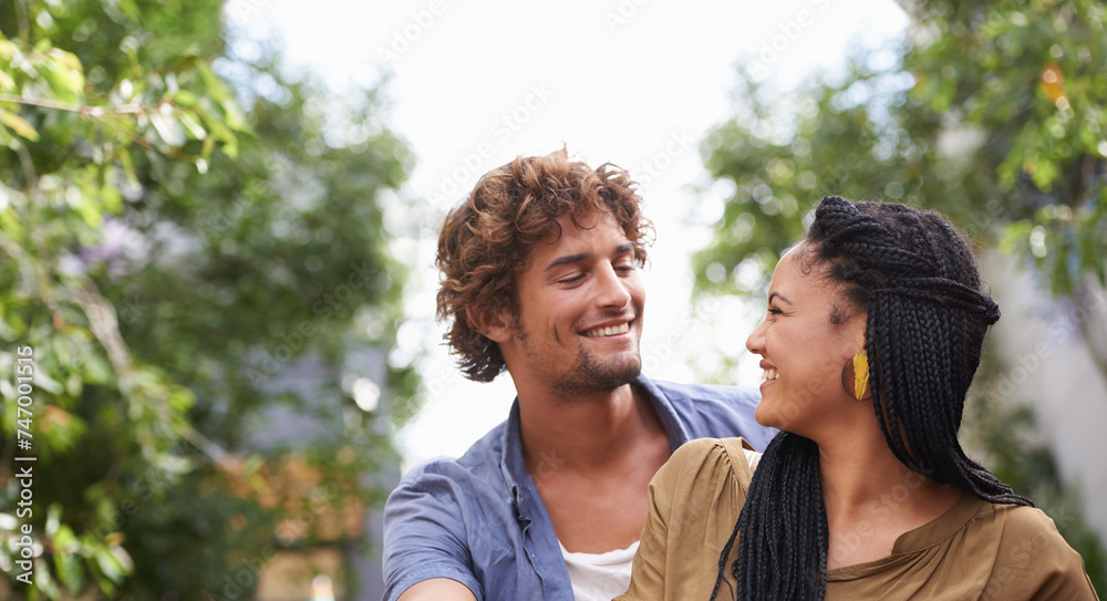 Interracial, couple and smile together in nature, happy and love in diversity people with tree in backyard. Happiness, affection or staring, outdoor for relationship growth or commitment for romance Interracial, couple and smile together in nature, happy and love in diversity people with tree in backyard. Happiness, affection or staring, outdoor for relationship growth or commitment for romance