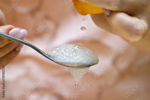 A squeezed drop of lemon juice flying into a spoon filled with baking soda. Abundant foam