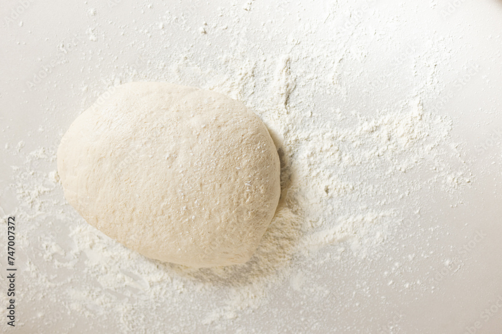 A ball of dough sits amidst a dusting of flour on a surface with copy space A ball of dough sits amidst a dusting of flour on a surface with copy space