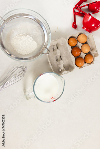 Ingredients for baking are neatly arranged on a white surface with copy space