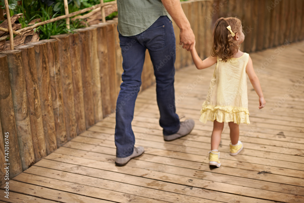 Little girl, father and holding hands with parent for bonding, adventure or fun field trip. Rear view of young child or kid walking with dad for safety, protection or sightseeing together in nature Little girl, father and holding hands with parent for bonding, adventure or fun field trip. Rear view of young child or kid walking with dad for safety, protection or sightseeing together in nature