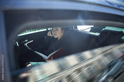 Asian business woman working in back of a car