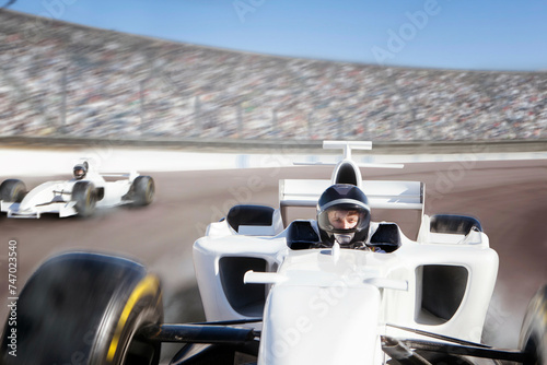 Racecar driver in focus speeding on a track with competitors in pursuit 