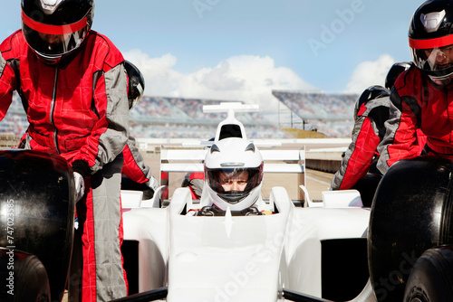 Focused driver gearing up for the race with pit crew readying the car. 