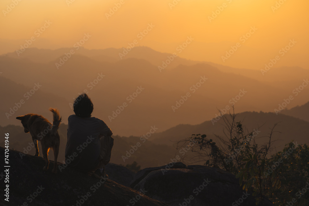 landscape and travel concept with solo freelancer man relax and play with dog at top of mountain and sunset with layer of mountain