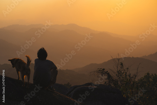 landscape and travel concept with solo freelancer man relax and play with dog at top of mountain and sunset with layer of mountain