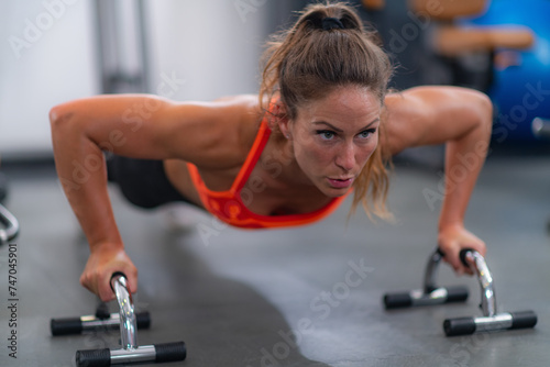 Female athlete performing push-ups in the gym, showcasing strength and dedication to fitness.