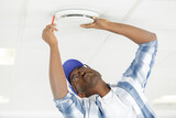 technician marking to install smoke detector on ceiling at home