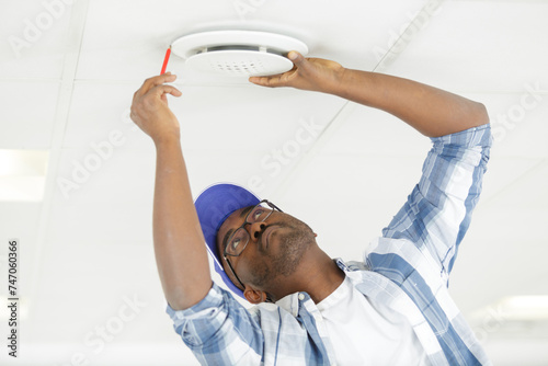 technician marking to install smoke detector on ceiling at home photo