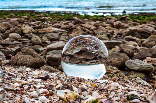 glass ball lens lies on the sand of the sea shore