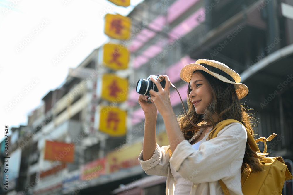Young female traveller photographing local city street scene with camera