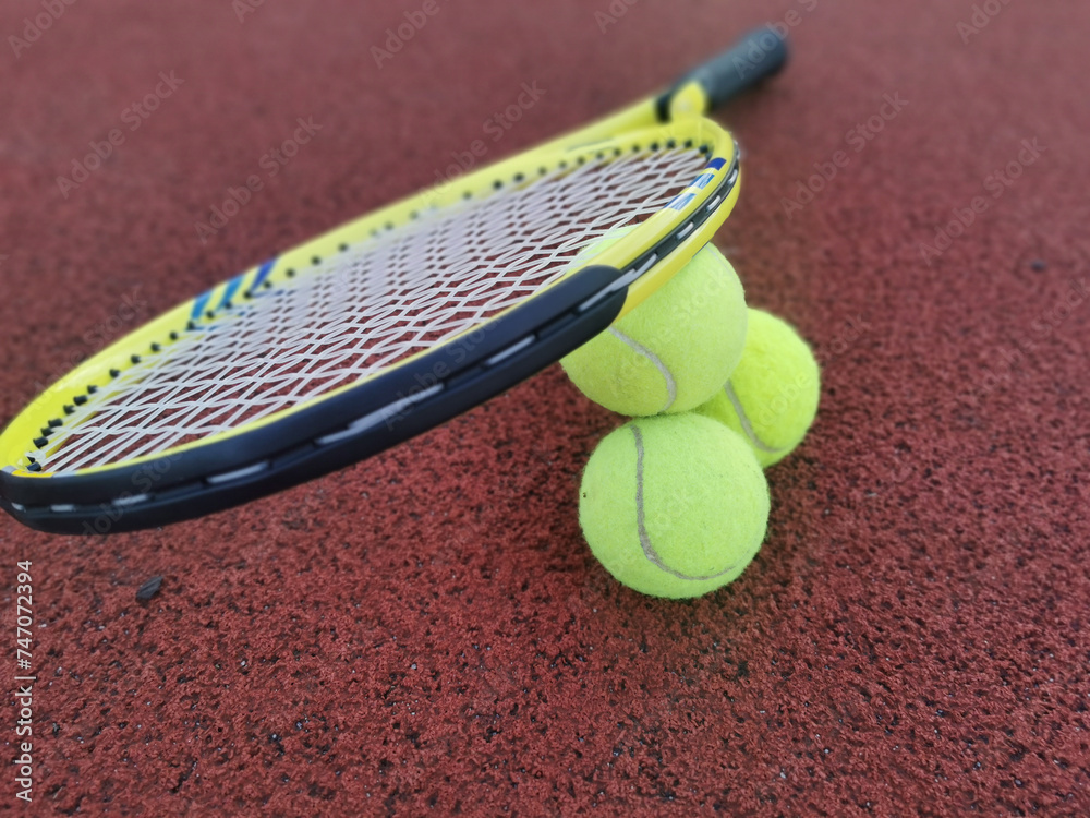 Tennis. Tennis ball and racket on a red background of tennis court with copy space. Sport and healthy lifestyle. The concept of outdoor game sports. 
