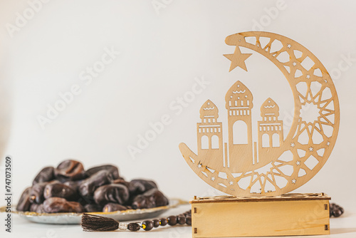 Wooden decor for Ramadan Kareem holiday on a light background with rosary and dates