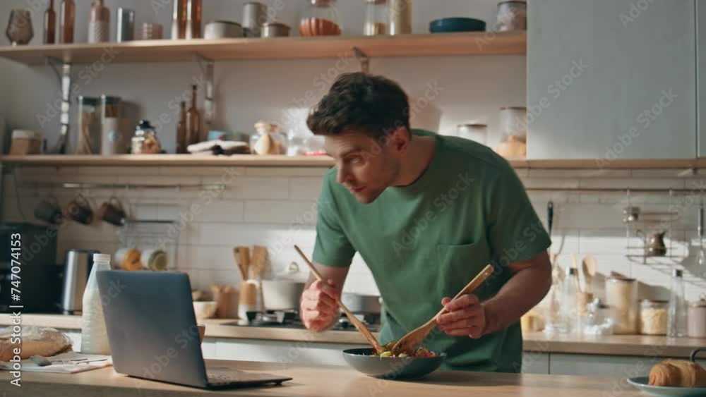 Young man watching video cooking in big kitchen closeup. Hipster looking laptop Young man watching video cooking in big kitchen closeup. Hipster looking laptop