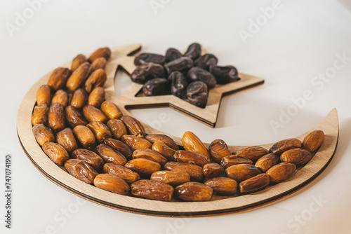 Dried dates on a wooden tray in the shape of a month and a star. Ramadan kareem background