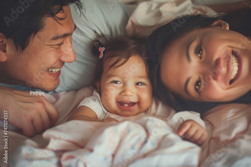Happy family with cute little kid daughter having fun laughing in bed, happy family concept