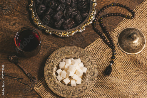 Glass of tea with sugar and dried dates on a wooden background with burlap. Ramadan Kareem holiday background. Halal meal set for fasting is obligatory for Muslim on wooden. . Soft focus. Shallow DOF. photo