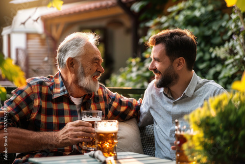 Happy man talks to his senior father while drinking beer together on patio