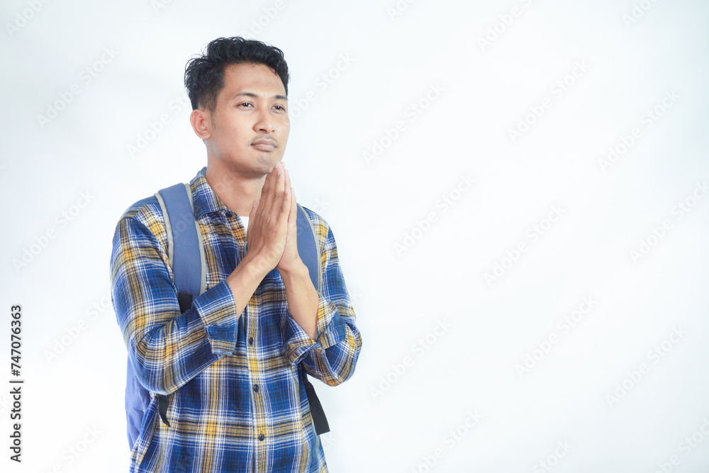 religious young Asian student man wearing casual clothes with backpack, hand folded in prayer gesture begging about something isolated on white background. High school university college concept religious young Asian student man wearing casual clothes with backpack, hand folded in prayer gesture begging about something isolated on white background. High school university college concept