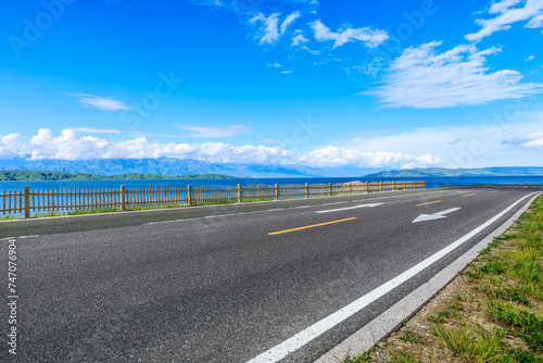 Asphalt road and blue lake with mountain nature landscape under blue sky