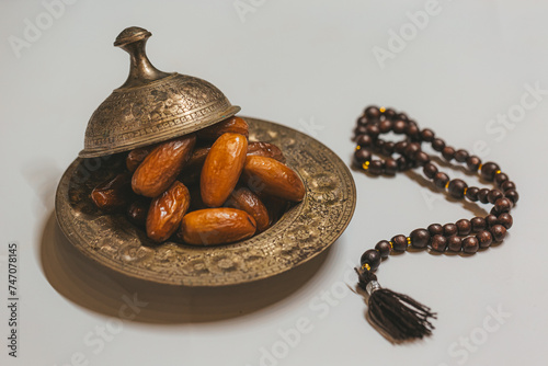 Bronze plate with dates and wooden rosary on a light background. Ramadan background. Ramadan kareem.
