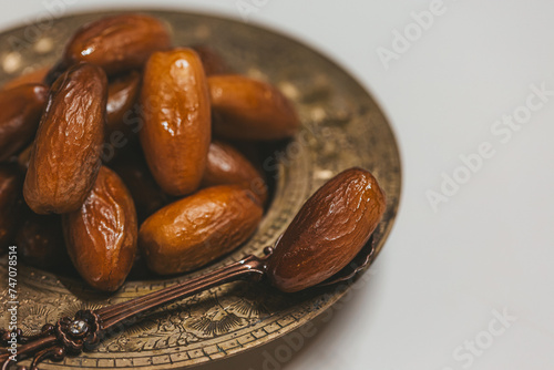 Bronze plate with dried dates and spoon, close-up. Ramadan Kareem holiday concept