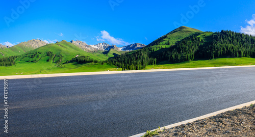 Asphalt highway road and green forest with mountain nature landscape under blue sky