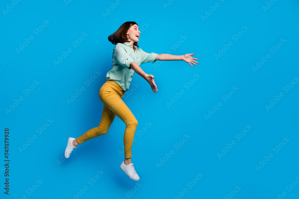 Full length photo of overjoyed woman dressed teal shirt yellow trousers run to empty space catch object isolated on blue color background