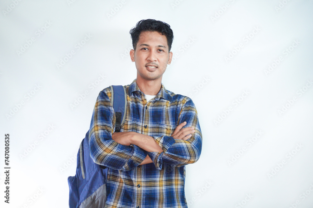 Smiling confident young Asian man student wearing casual clothes and backpack folded hands and looking on camera isolated on white background. high school university college concept Smiling confident young Asian man student wearing casual clothes and backpack folded hands and looking on camera isolated on white background. high school university college concept