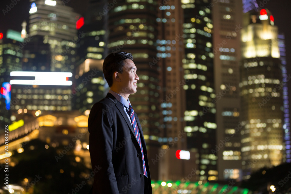 Fototapeta premium Chinese businessman standing outdoors at night.