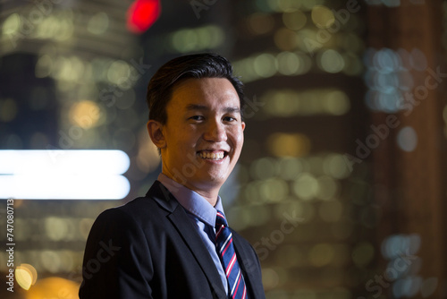 Chinese businessman standing outdoors at night.