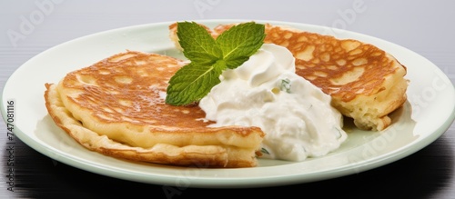A white plate holds cottage cheese pancakes covered in a dollop of whipped cream. The pancakes are fluffy and topped with a rich, creamy layer of dairy goodness.