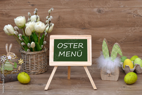 Ein Strauß Tulpen mit Ostereiern und dem Text Ostermenü auf einer Tafel.