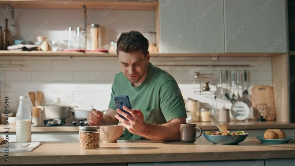 Happy man reading cellphone message kitchen counter closeup. Businessman eating Happy man reading cellphone message kitchen counter closeup. Businessman eating