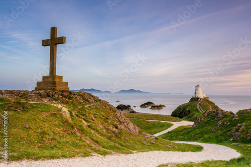 Ynys Llanddwyn Lighthouse and a religous cross, at sunset on a summers day. North Wales, Anglesey photo