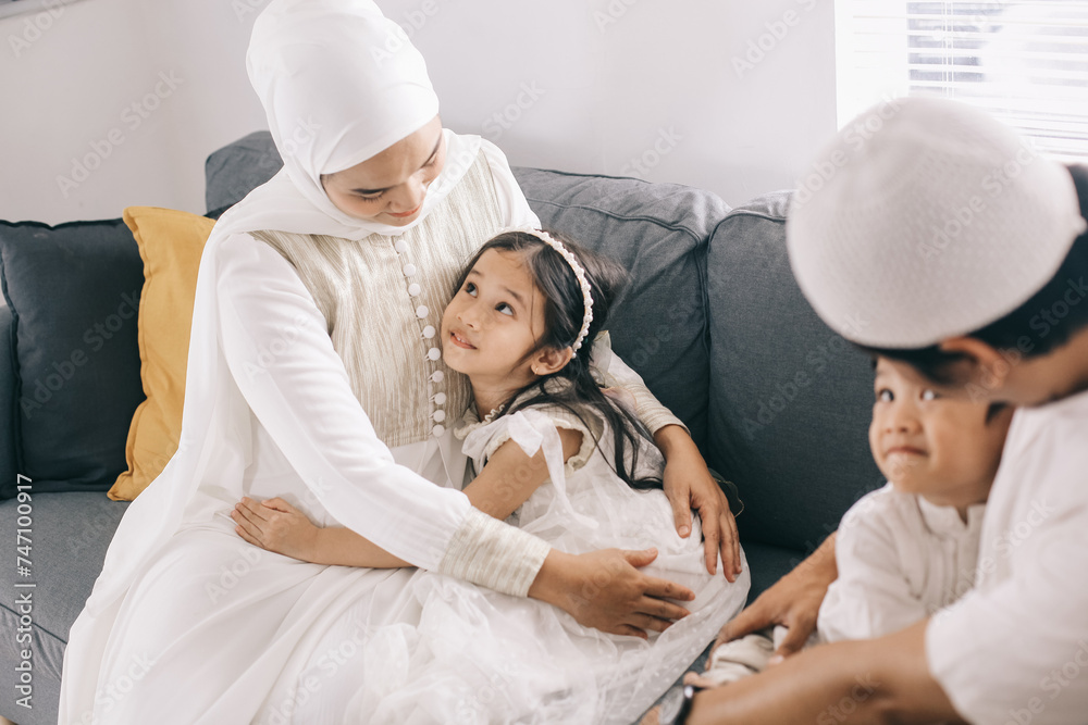 Happy Muslim children hugging their parents during Eid Mubarak while sitting together on the sofa in the living room. Happy Muslim children hugging their parents during Eid Mubarak while sitting together on the sofa in the living room.