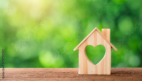House wood with heart shape on wooden and green background, copy space