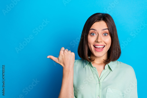 Photo of impressed woman with bob hairstyle dressed turquoise shirt indicating at sale empty space isolated on blue color background