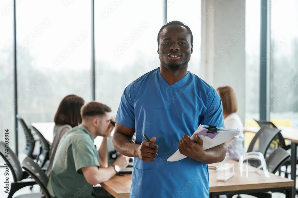 Obraz premium Black man is standing in front of colleagues. Group of doctors are together indoors