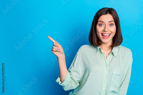 Photo of positive woman with bob hairstyle dressed turquoise shirt indicating at discount empty space isolated on blue color background