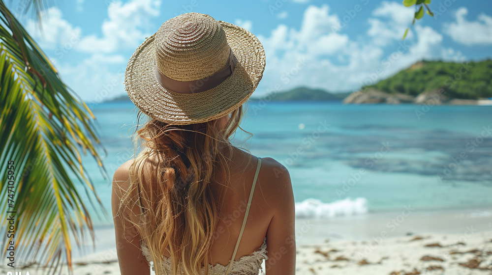 A woman in a hat relaxes on the seashore near palm trees. Summer beach holiday concept on a hot sunny day