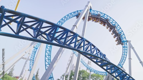 Roller coaster Ride against blue sky. Roller coaster in the amusement park. Cheerful entertainments in park of attractions