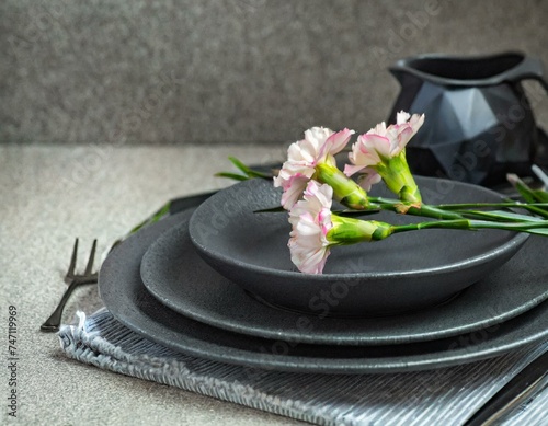 Place setting with grey crockery and pink carnation flowers