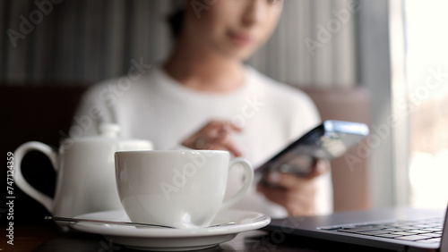 Business woman working online in a modern coffee shop with a smartphone in her hands and a laptop. Concept of freelancing, business, negotiations and remote work.